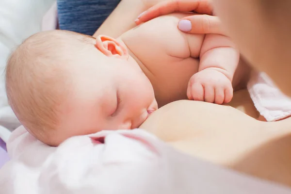 Mother breastfeeding her newborn baby in a bed — Stock Photo, Image