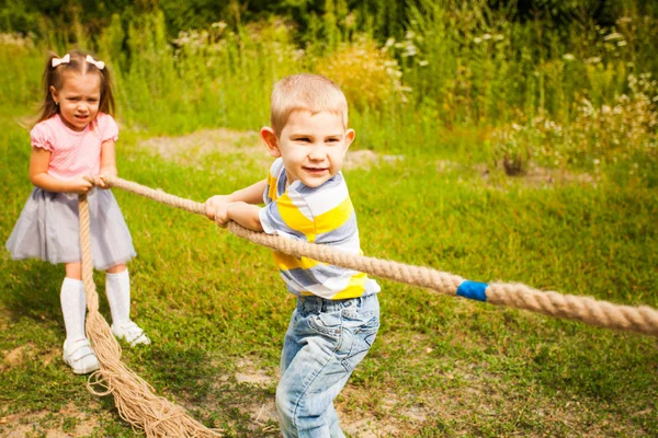Счастливая группа детей, играющих в перетягивание каната в парке — стоковое фото