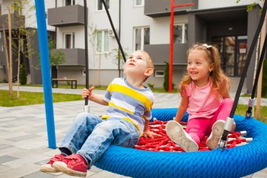 Cute little children on swing at modern playground