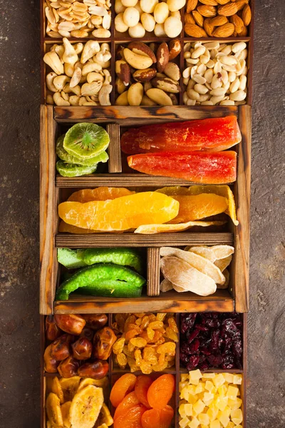 Variety of dried fruits and assorted nuts in a wooden box, view from above. — Stockfoto