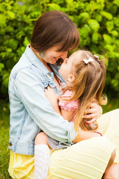 Feliz madre e hija abrazándose y besándose en el parque de verano . —  Fotos de Stock