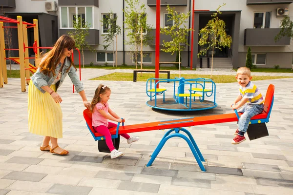 Счастливая мать играет с детьми на детской площадке — стоковое фото