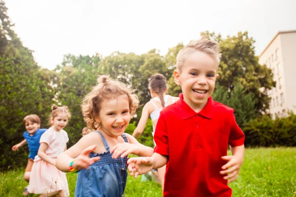 As crianças correm e brincam em um prado em uma festa de aniversário de crianças — Fotografia de Stock