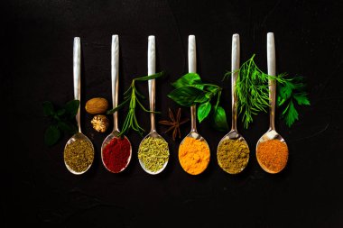 Siyah masada çeşitli baharat kaşıkları, üst görünüm.