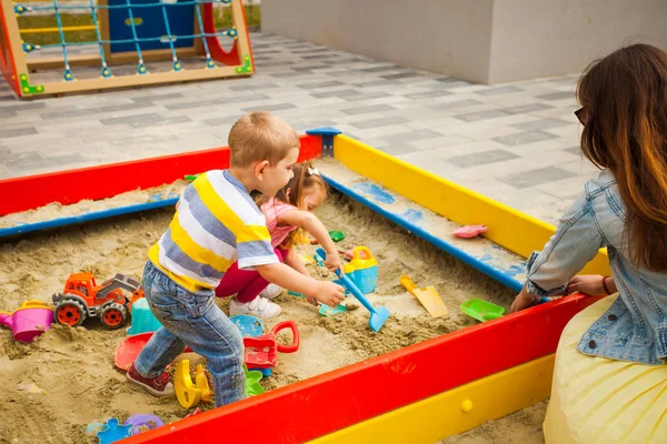 Menino e menina feliz brincando na areia no playground ao ar livre. Infância feliz e saudável — Fotografia de Stock