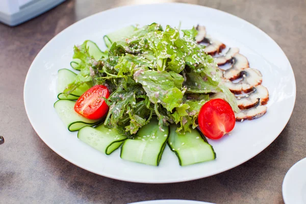 Finom friss angolnás saláta, arugulával, salátával és paradicsommal, fehér tálcán — Stock Fotó
