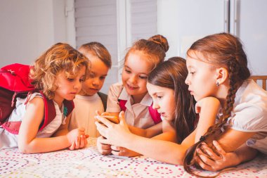 Akıllı telefonlu bir grup okul çocuğu, tatilde sınıfta eğleniyor.