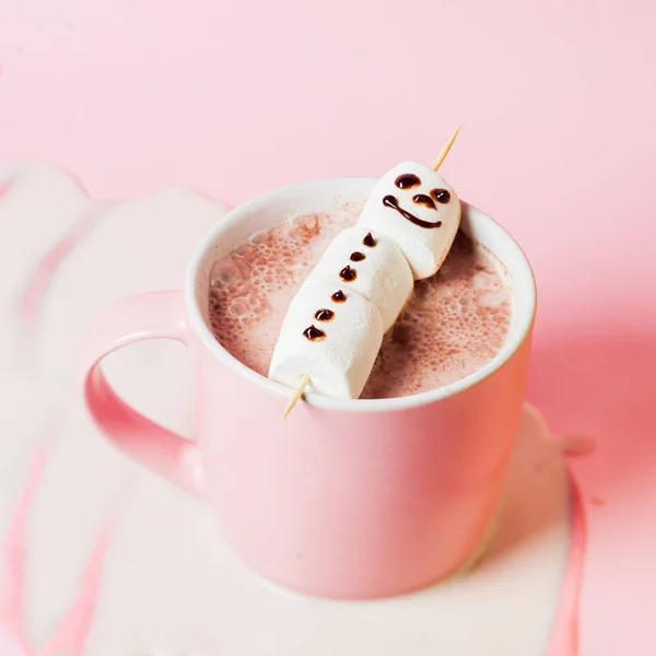 Hot cocoa with marshmallow snowman in a pink mug on a pink background — Stock Photo, Image