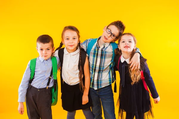 Migliori amici di scuola che si abbracciano insieme. Compagni di classe sorridenti felici in piedi sul muro giallo — Foto Stock
