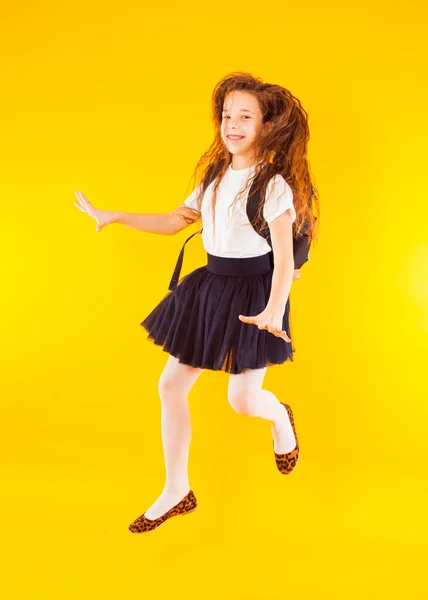 Schoolgirl jumping high over yellow background. Back to school. Happy girl ready to study with backpack — 图库照片