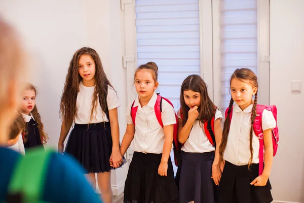 Grupo de alunas de mãos dadas durante a pausa no corredor. Bullying escolar — Fotografia de Stock