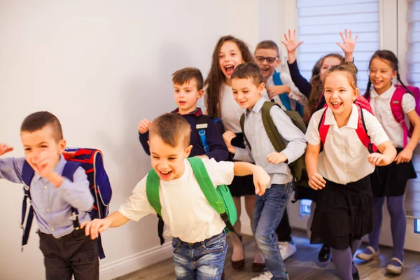 Gelukkige schoolkinderen rennend in de lagere school hal, vooraanzicht — Stockfoto