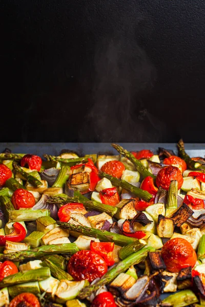 Hortalizas calientes asadas en el horno. Rebanadas mixtas de espárragos, tomates, calabaza, cebolla y aceite de oliva en una bandeja para hornear —  Fotos de Stock