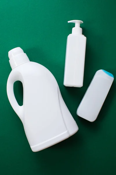 Plastic bottles of cleaning products over green background. Top view. Flat lay. — ストック写真