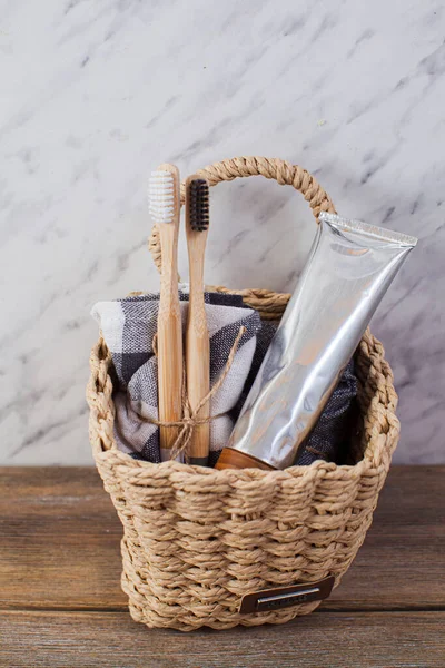 Eco natural bamboo toothbrushes and organic toothpaste in a basket in bathroom. — Stockfoto