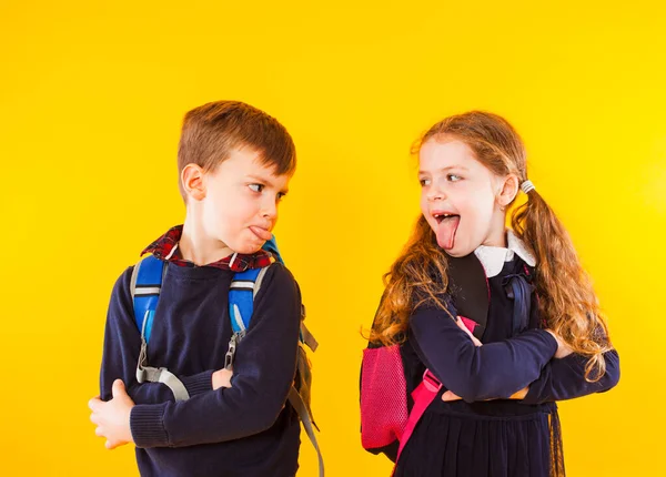 Grappige kinderen in schooluniform hebben plezier samen. Kinderen die elkaar tongen — Stockfoto