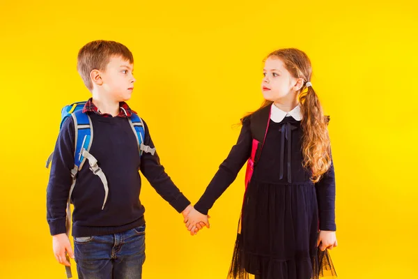 Back to school concept. Brother and sister holding hands and looking on each other over yellow — 图库照片