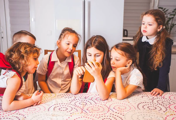 Nette Schüler, die sich in der Pause unterhalten und das Smartphone benutzen. glückliche Freunde, die zusammen Spaß haben — Stockfoto