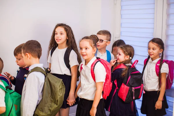 Grupo de niños de primaria con mochilas en el pasillo de la escuela. Regreso a la escuela —  Fotos de Stock