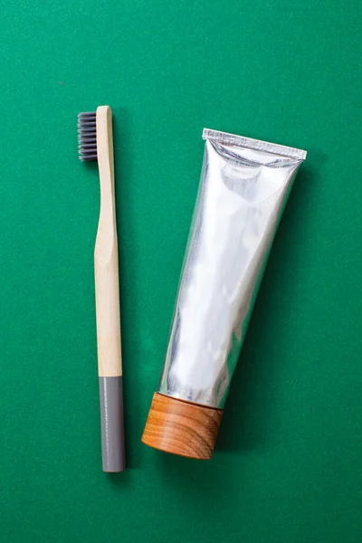 Bambusowa szczoteczka do zębów i organiczna pasta do zębów na zielonym tle — Zdjęcie stockowe