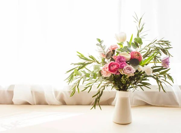 Belo buquê de flores delicado com rosas, eustomas e folhas de eucalipto em um vaso em um peitoril da janela — Fotografia de Stock