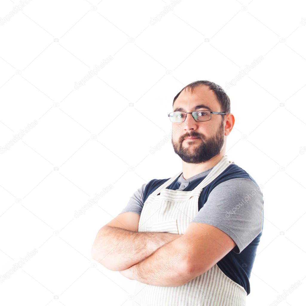 Confident young handsome man in apron keeping arms crossed and standing against white background