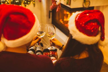 Noel Baba şapkalı evli çift şöminenin yanında.