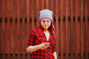 Genç kız müzik dinliyor ve caddede modern akıllı telefon aygıtı kullanıyor..