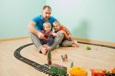 Mutlu baba ve oğullar evlerinde oyuncak demiryolu ile oynuyorlar.