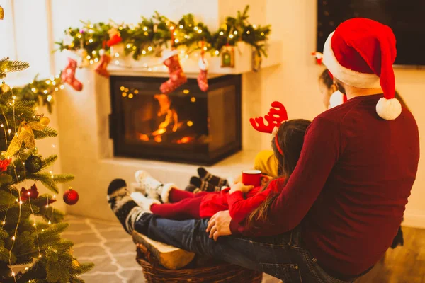 Uomo vista posteriore seduto con i bambini vicino al camino — Foto Stock