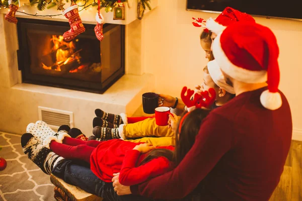 Familia cerca de la chimenea tomando té, celebrando la Navidad —  Fotos de Stock