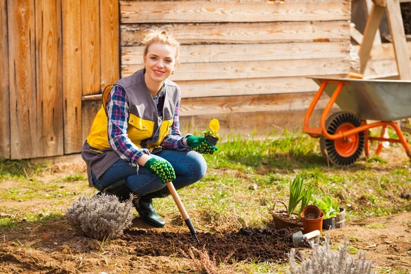 Jonge vrouw werken in haar tuin knielen — Stockfoto