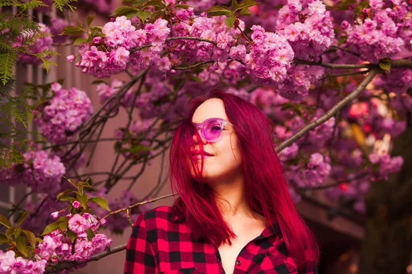 Vrouw model met prachtige haarkleur op sakura bloesem achtergrond — Stockfoto