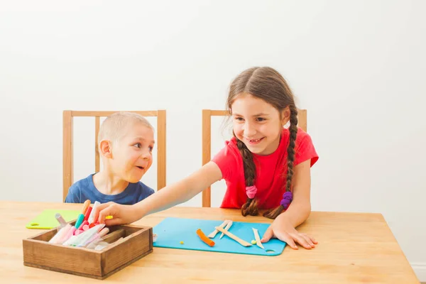 Menino e menina aprendendo a usar massa de jogo colorido — Fotografia de Stock