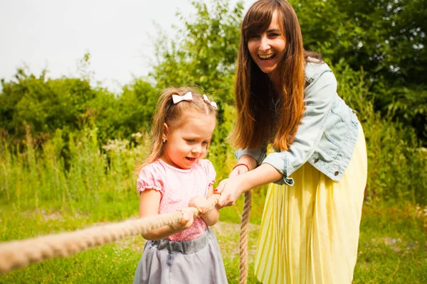 Happy mother helps her daughter playing tug of war — 스톡 사진