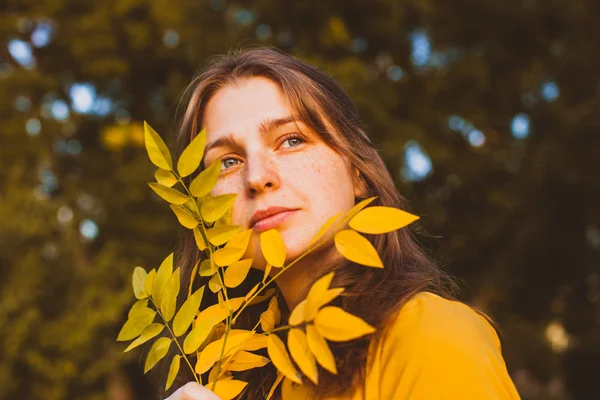 Gelbes Blatt auf dem weiblichen Gesicht im Park — Stockfoto