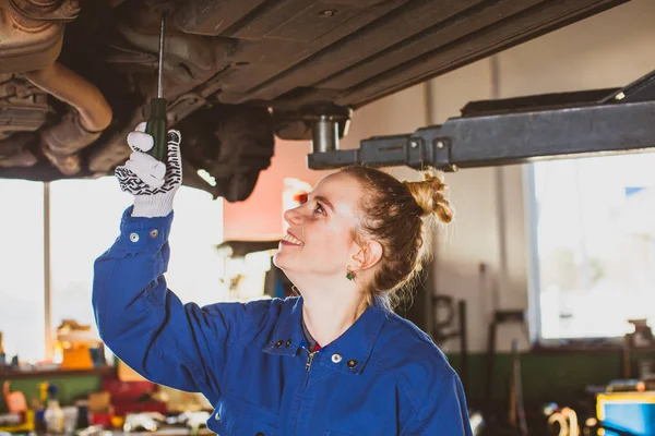 Женщина-механик ремонтирует машину в гараже — стоковое фото