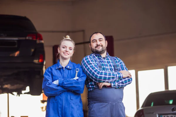 Уверенные молодые механики мужчина и женщина в гараже — стоковое фото