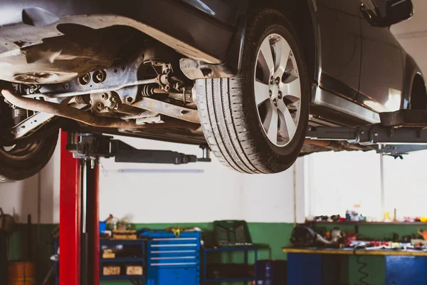 Vehicle raised on lift at maintenance station — Stock Photo, Image