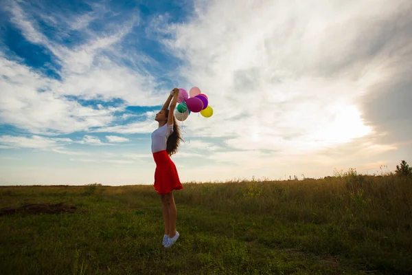 Adolescente chica con globos de pie en el campo — Foto de Stock