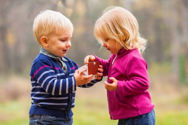 Küçük ikizler el ele tutuşuyor. Açık havada küçük bir ev modeli. Emlak ve aile evi
