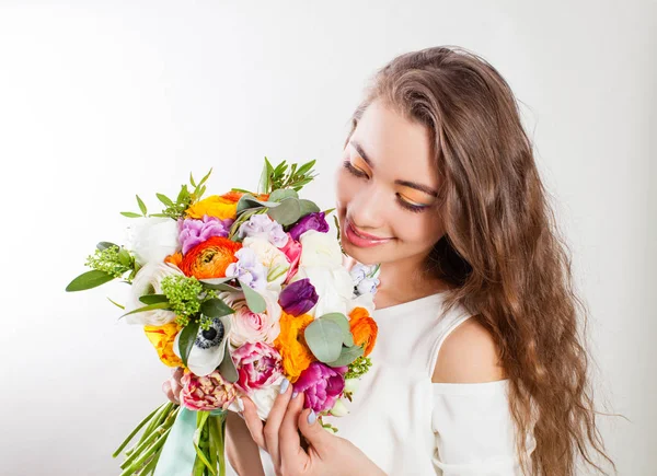 Uzun kıvırcık saçlı genç kadın çiçek buketinin tadını çıkarıyor. — Stok fotoğraf
