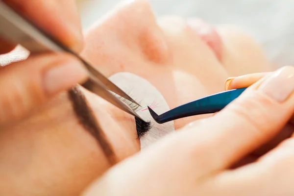 Esteticista haciendo pestañas artificiales. procedimiento de extensión de pestañas — Foto de Stock