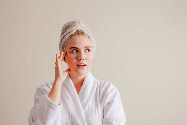 Красивая девушка трогает лицо и смотрит в сторону
