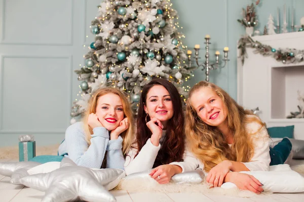 Three young woman on a floor near fir tree — Stock Photo, Image