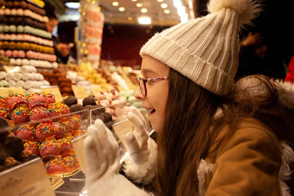 Linda chica cerca de soporte dulce con caramelos de chocolate — Foto de Stock
