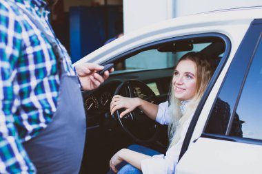 Otomotiv servisinde genç bir kadın sürücü arabada oturuyor.