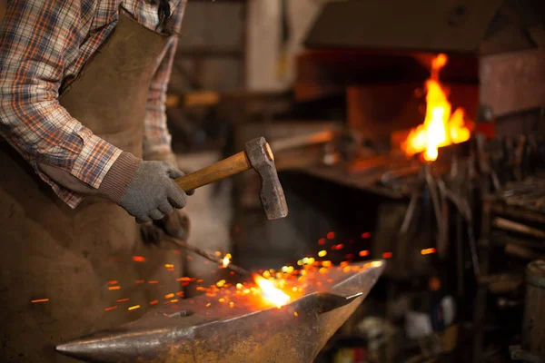 Herrero forjando el metal fundido en el yunque en la herrería — Foto de Stock