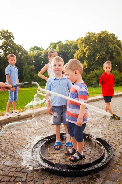 Glückliche Jungs stehen gemeinsam in großer Seifenblase — Stockfoto