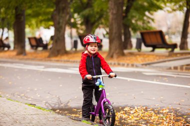 Bisiklette oturan küçük bir çocuğun portresi.